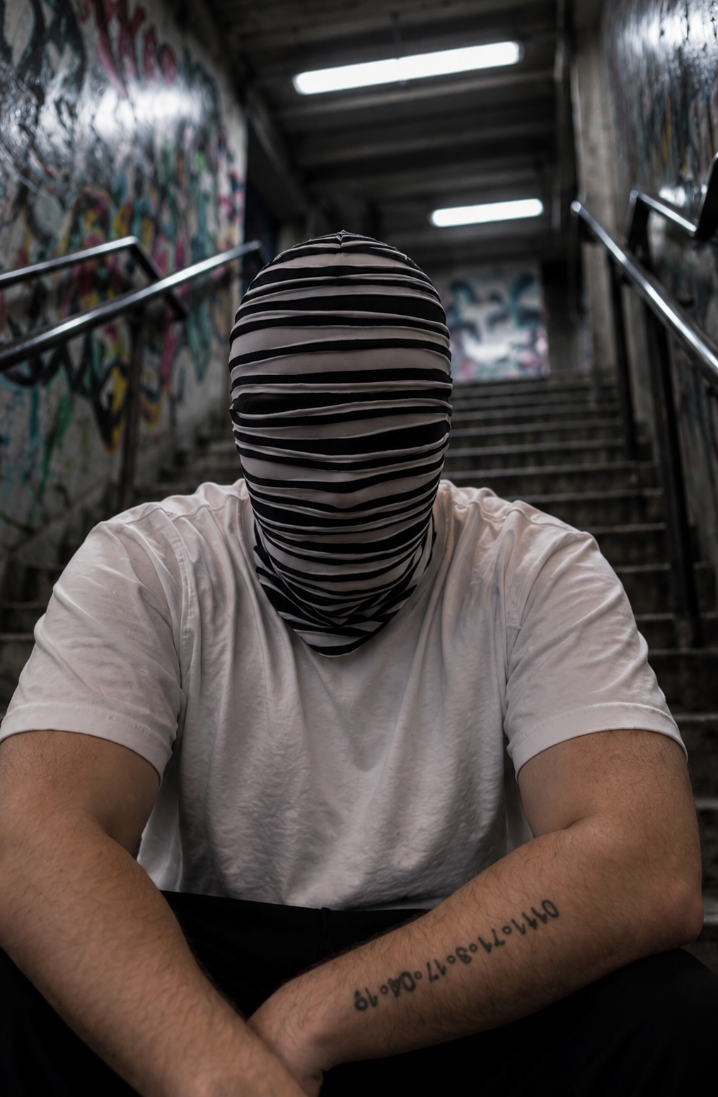 OTKYDACH black and white striped full face mask worn in an underground graffiti stairwell